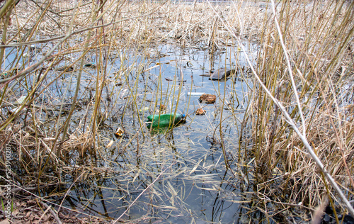 Garbage lies in the water on one of the urban landscape. plastic bottles were thrown into the water. Garbage in the water. Environmental plastic pollution. Ecological catastrophe of planet Earth.