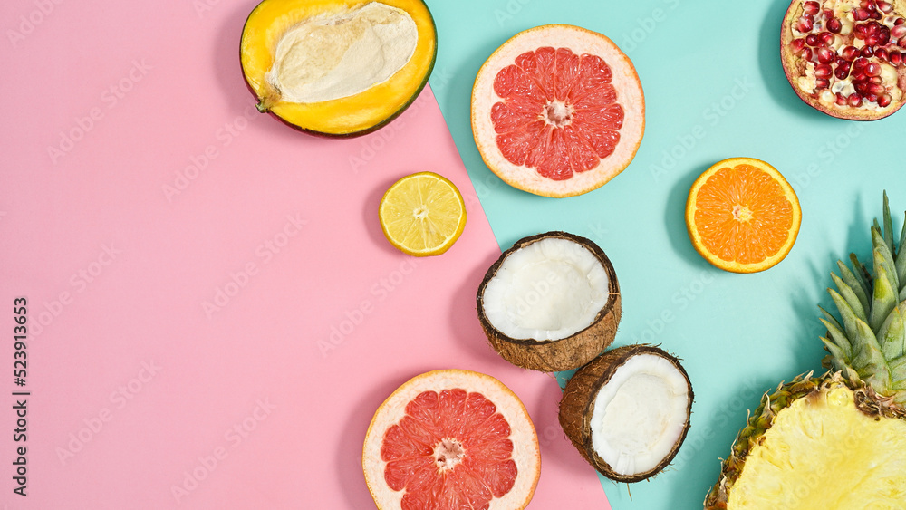 Ripe organic half sliced tropic fruits on pastel pink and cyan background. Flat lay. Copy space. Summer cncept