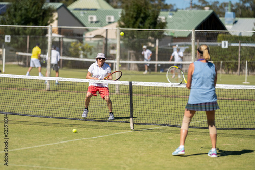 Play a social doubles tennis match on a grass tennis court in a tournament 