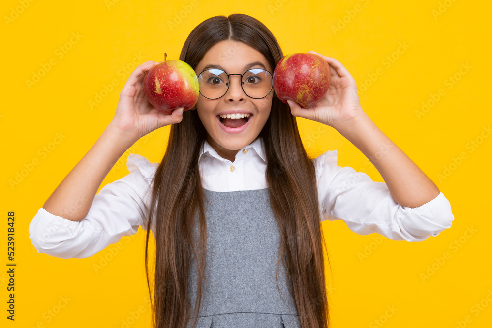 Child girl eating an apple over isolated yellow background. Tennager with fruit. Happy girl face, positive and smiling emotions. Child girl eating an apple over isolated yellow background. Tennager with fruit. Happy girl face, positive and smiling emotions.