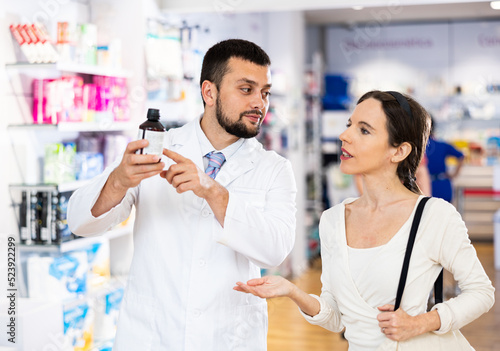 Young adult man pharmacist consulting woman customer about products at pharmacy