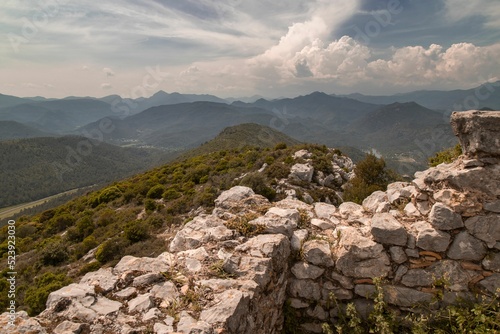 Scenic view of a stone wall on top of a green mountain in Sant Llorenc de la Muga, Spain photo