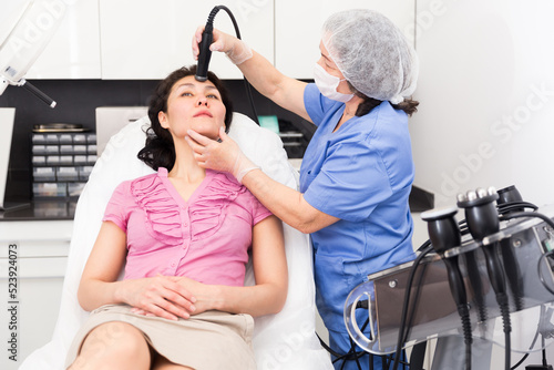 Obraz na plátně Asian female client getting professional face skin rf lifting procedure on modern equipment in clinic of aesthetic cosmetology