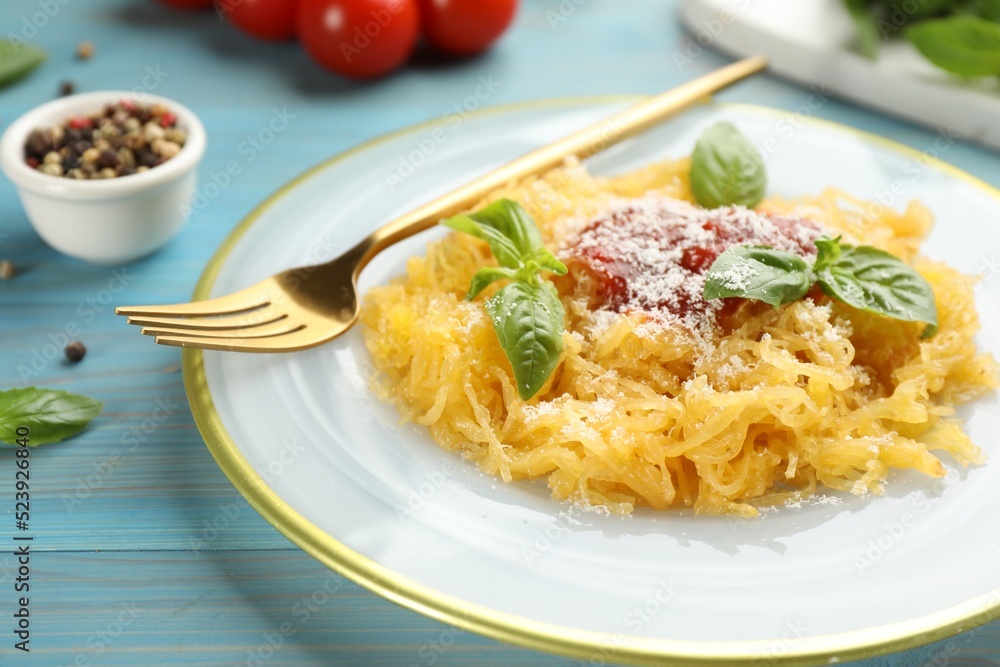 Tasty spaghetti squash with tomato sauce, cheese and basil served on light blue wooden table, closeup Tasty spaghetti squash with tomato sauce, cheese and basil served on light blue wooden table, closeup