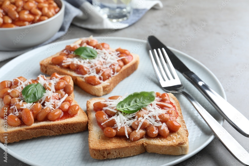 Toasts with delicious canned beans on light grey table Toasts with delicious canned beans on light grey table