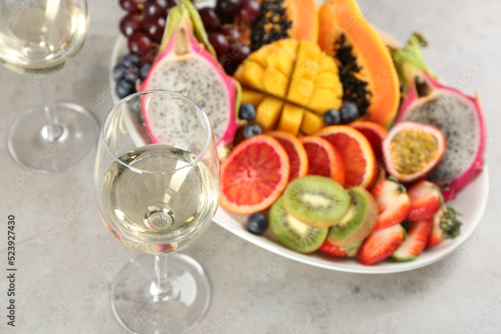 Delicious exotic fruits and wine on grey table Delicious exotic fruits and wine on grey table