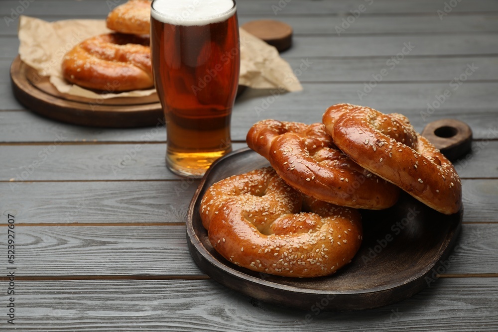 Tasty freshly baked pretzels and glass of beer on grey wooden table. Space for text Tasty freshly baked pretzels and glass of beer on grey wooden table. Space for text