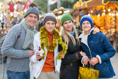 Portrait of happy family with christmas tinsel and gifts at a street fair