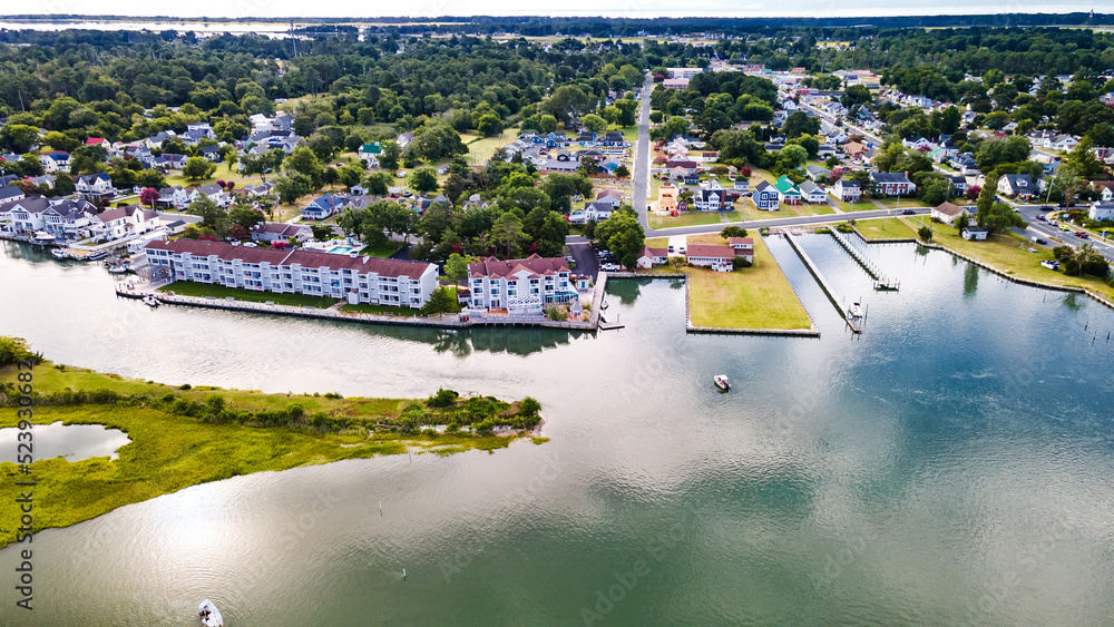 Chincoteague Island, marinas, houses and motels with parking lots. Road along the bay. Drone view.