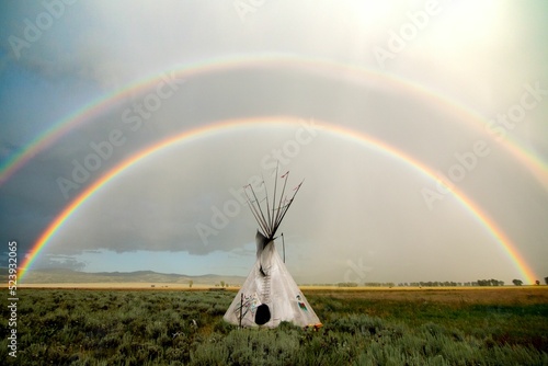 White conical tent resembling a tipi against the rainbow background photo