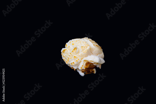 A horizontal photo of an isolated round shaped popcorn with part of the corn husk, an image of round popcorn on a black background.