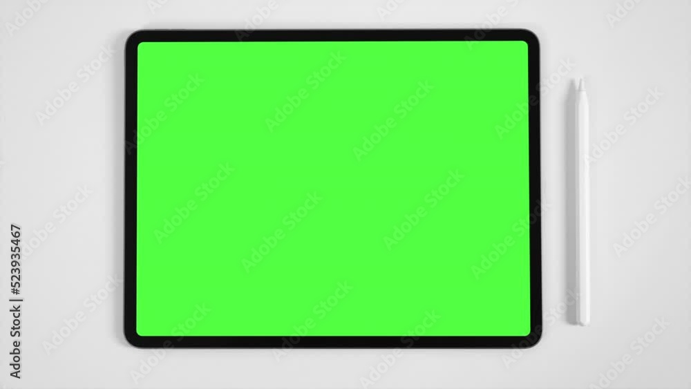 Zoom in mockup of tablet and digital pencil with pre-keyed green screen on white table. Zoom in mockup of tablet and digital pencil with pre-keyed green screen on white table.