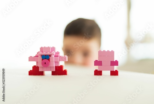 Selective focus shot of Kirby models made of blocks and a kid looking them on the blurry background photo