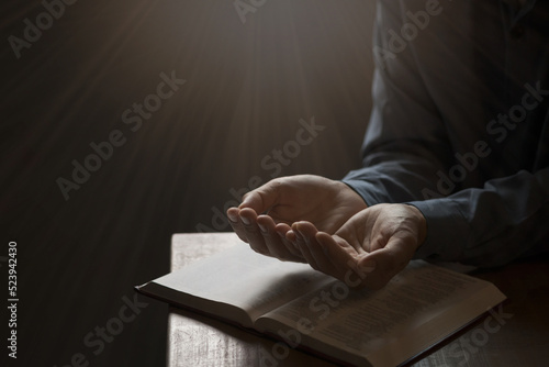 Photography Man praying on holy bible in the morning have a Yellow lights and sparkles coming