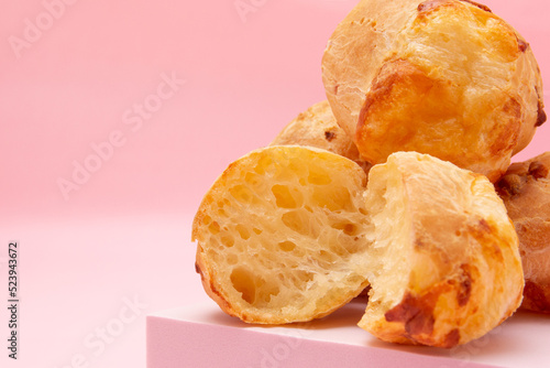 A pile of cheese breads on a podium, Brazilian tradicional Pao de Queijo, from Minas Gerais, on pink background photo