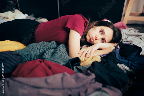 Fotografia Unhappy Woman Sitting on the Floor on a Pile of Clothes