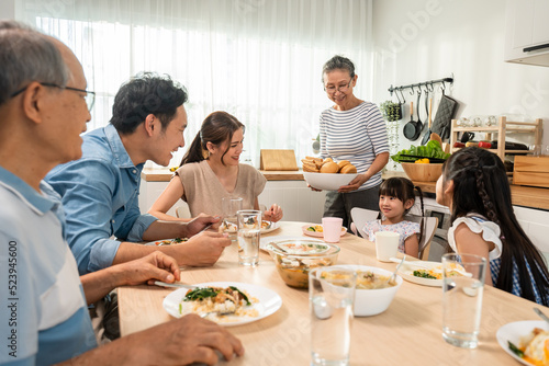 Asian big happy family having lunch on eating table together in house. 