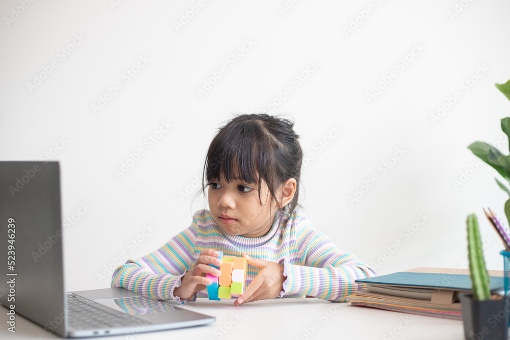 NAKHON RATCHASIMA, THAILAND - JULY 14, 2022:Asian little cute girl holding Rubik's cube in her hands. Rubik's cube is a game that increases the intelligence of children. NAKHON RATCHASIMA, THAILAND - JULY 14, 2022:Asian little cute girl holding Rubik's cube in her hands. Rubik's cube is a game that increases the intelligence of children.