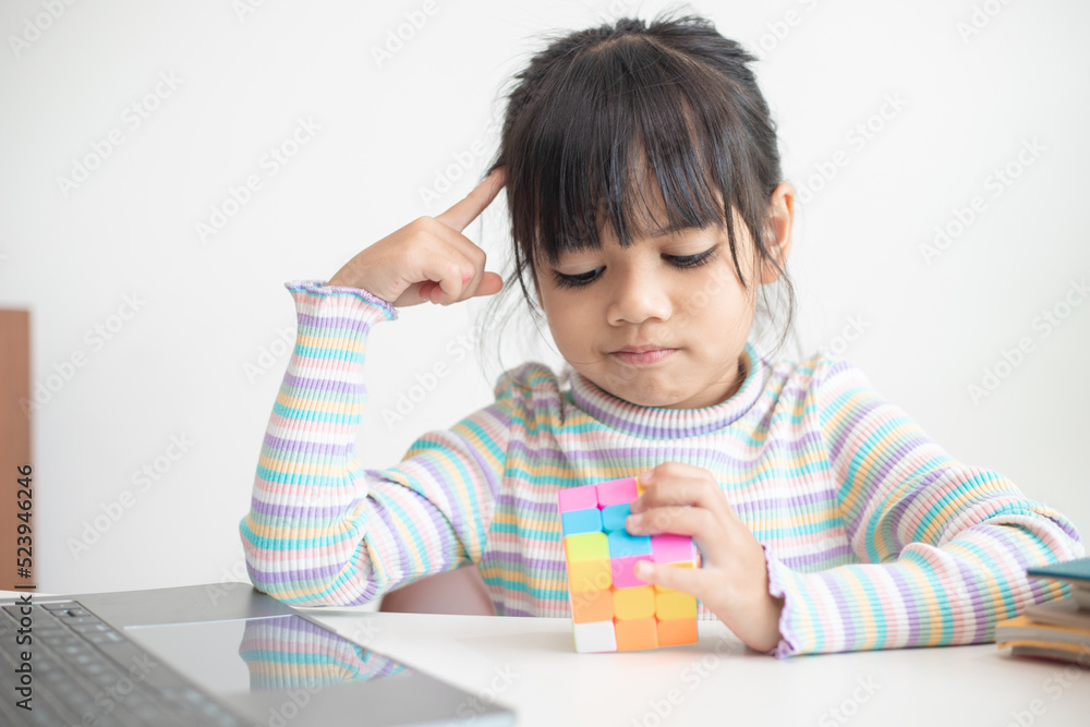 NAKHON RATCHASIMA, THAILAND - JULY 14, 2022:Asian little cute girl holding Rubik's cube in her hands. Rubik's cube is a game that increases the intelligence of children. NAKHON RATCHASIMA, THAILAND - JULY 14, 2022:Asian little cute girl holding Rubik's cube in her hands. Rubik's cube is a game that increases the intelligence of children.
