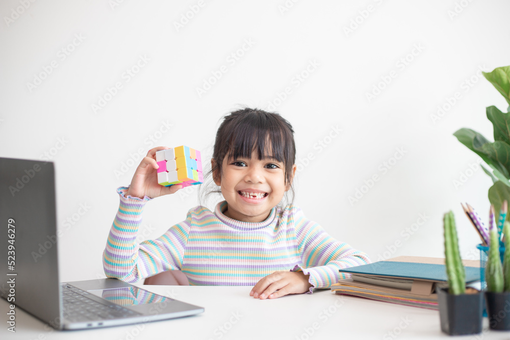 NAKHON RATCHASIMA, THAILAND - JULY 14, 2022:Asian little cute girl holding Rubik's cube in her hands. Rubik's cube is a game that increases the intelligence of children. NAKHON RATCHASIMA, THAILAND - JULY 14, 2022:Asian little cute girl holding Rubik's cube in her hands. Rubik's cube is a game that increases the intelligence of children.