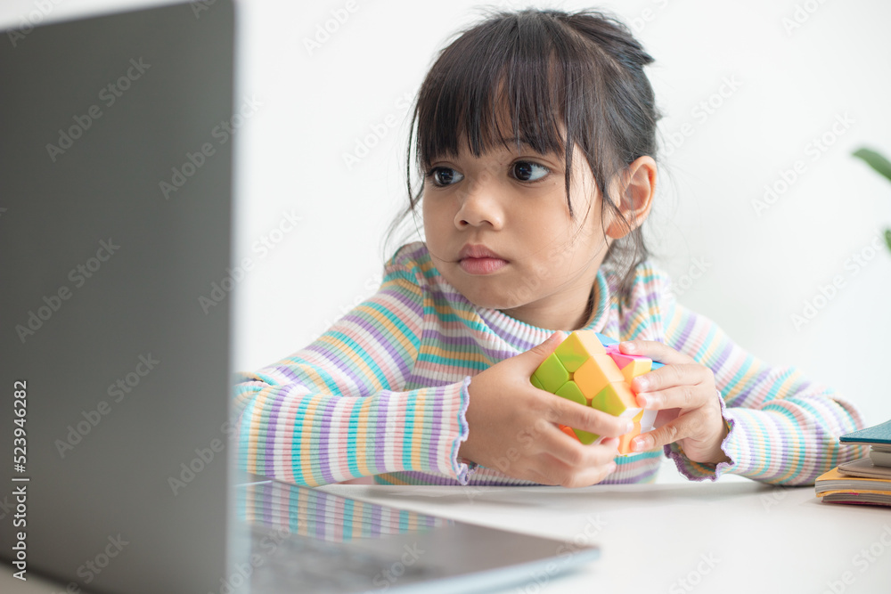 NAKHON RATCHASIMA, THAILAND - JULY 14, 2022:Asian little cute girl holding Rubik's cube in her hands. Rubik's cube is a game that increases the intelligence of children. NAKHON RATCHASIMA, THAILAND - JULY 14, 2022:Asian little cute girl holding Rubik's cube in her hands. Rubik's cube is a game that increases the intelligence of children.