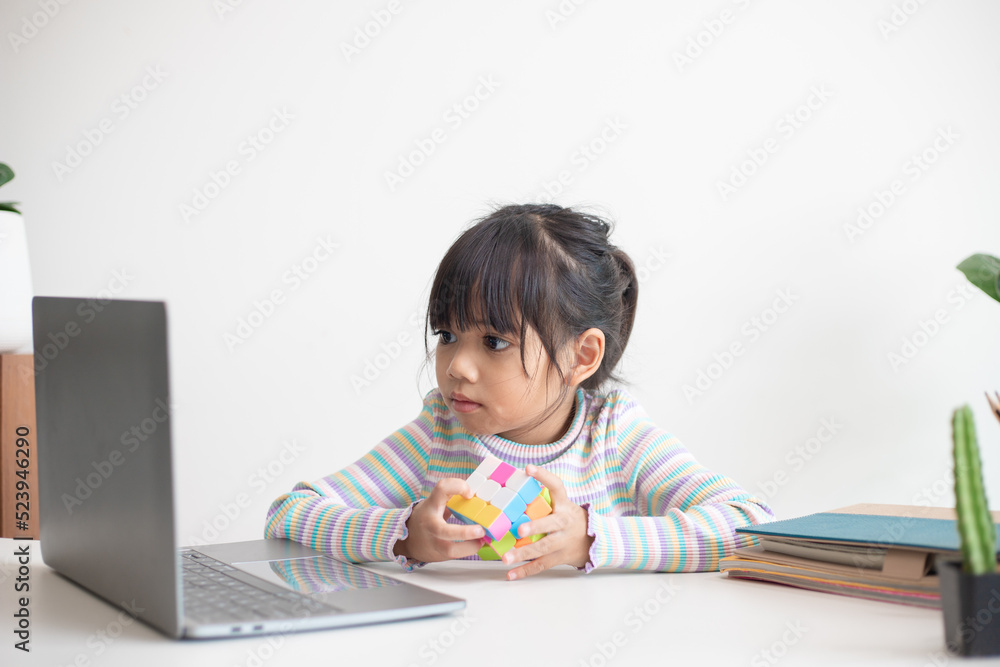 NAKHON RATCHASIMA, THAILAND - JULY 14, 2022:Asian little cute girl holding Rubik's cube in her hands. Rubik's cube is a game that increases the intelligence of children. NAKHON RATCHASIMA, THAILAND - JULY 14, 2022:Asian little cute girl holding Rubik's cube in her hands. Rubik's cube is a game that increases the intelligence of children.