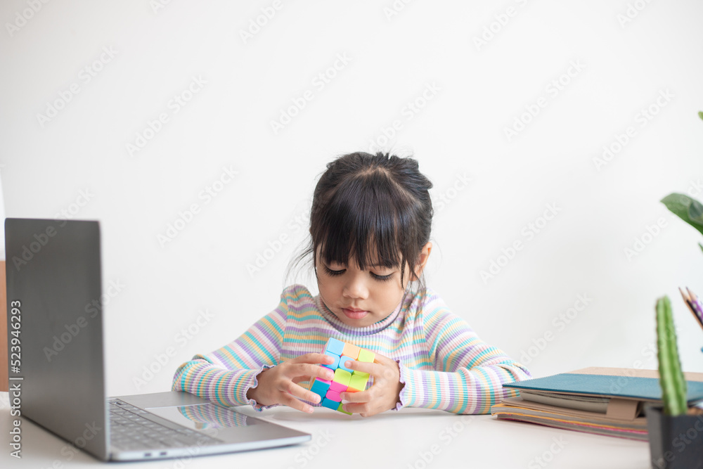 NAKHON RATCHASIMA, THAILAND - JULY 14, 2022:Asian little cute girl holding Rubik's cube in her hands. Rubik's cube is a game that increases the intelligence of children. NAKHON RATCHASIMA, THAILAND - JULY 14, 2022:Asian little cute girl holding Rubik's cube in her hands. Rubik's cube is a game that increases the intelligence of children.