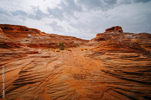 Red wavy sand stones, bluffs and cliifs at Glen Canyon National Recriation Area, Page, Arizona, and cloudy sky background