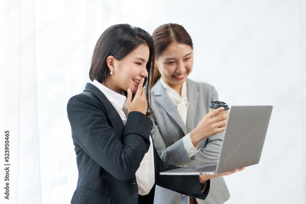 Two beautiful Asian young business women discuss work exchange idea exchange knowledge using laptop computer in the office. Two beautiful Asian young business women discuss work exchange idea exchange knowledge using laptop computer in the office.