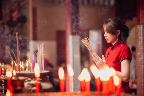 An Asian woman lighting incense sticks to pay homage to the Chinese New Year.