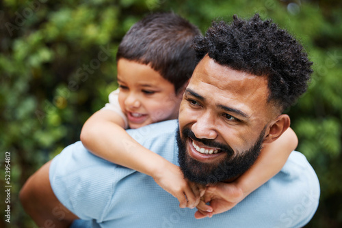 Happy father with son on piggyback while smiling, laughing and playing in a park outdoors. Cheerful, loving and caring dad relaxing, bonding and enjoying fun day with playful, cute and adorable boy © Allistair F/peopleimages.com
