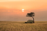 savanna grassland in africa during sunset with safari tourist travel car by tree