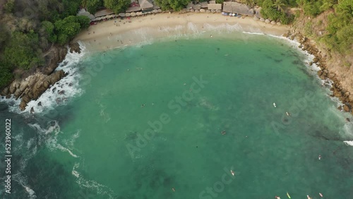 Drone shot of Playa Carrizalillo panning up from the beautiful water to the town and surroundings photo