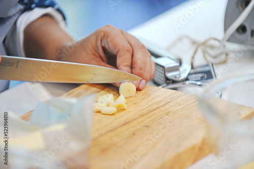 Almaty, Kazakhstan - 08.28.2015 : Slicing garlic slices on a wooden board in the kitchen.