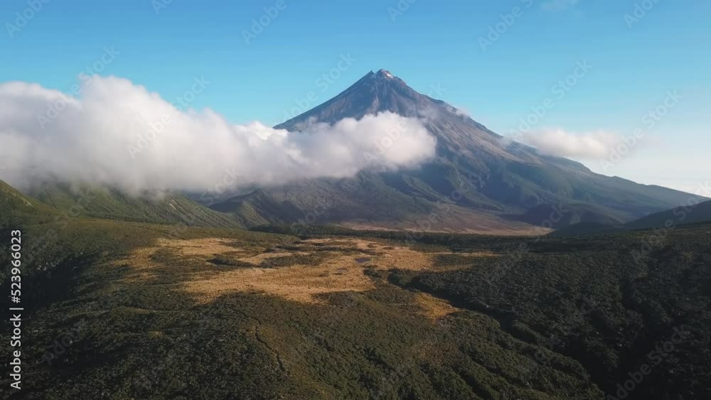 Scenic landscape with Mt Taranaki volcano in the background. Pulling back past clouds. New Zealand. Scenic landscape with Mt Taranaki volcano in the background. Pulling back past clouds. New Zealand.