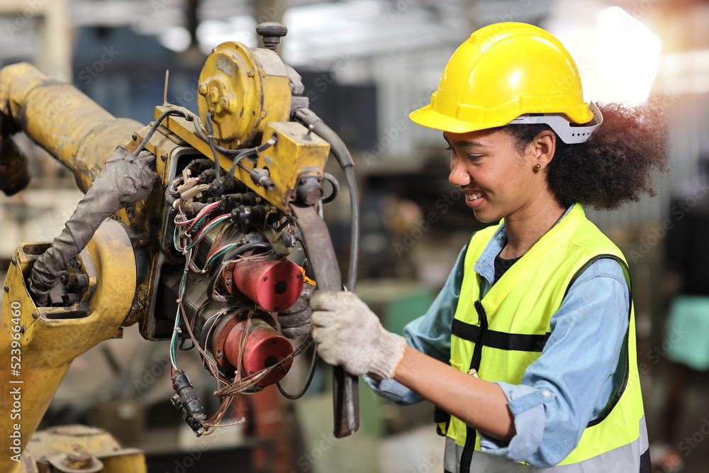 Fototapeta premium Professional heavy industry technician engineer in safety workwear repairing part of broken robot arm machine in intelligent factory automotive. Industrial and technology support system concept