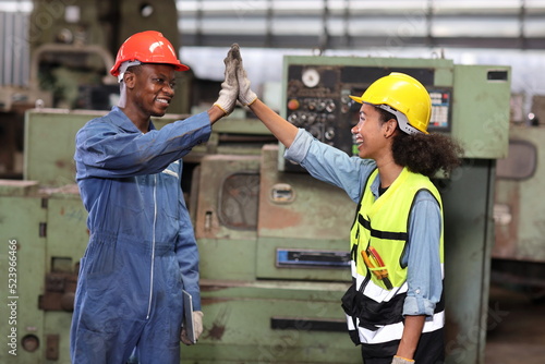 Happy smiling teamwork technician engineer or worker in protective uniform with hardhat give high five celebrate successful together completed deal commitment at heavy industry manufacturing factory