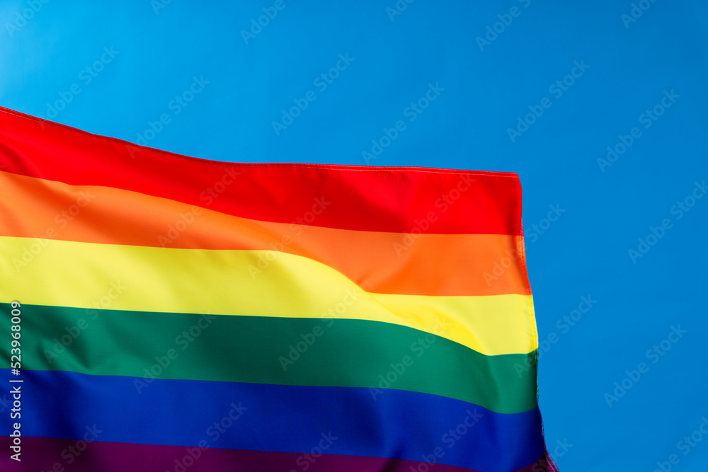 Rainbow flag waving on blue background Rainbow flag waving on blue background