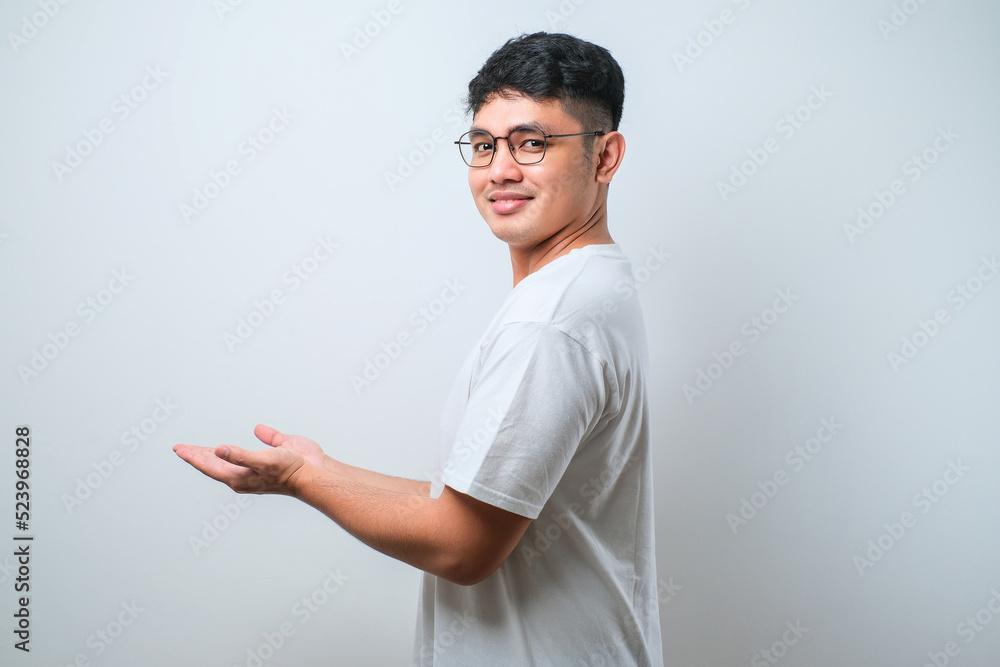 Young handsome asian man wearing casual shirt with a big smile on face, pointing with hand finger to the side looking at the camera. Young handsome asian man wearing casual shirt with a big smile on face, pointing with hand finger to the side looking at the camera.
