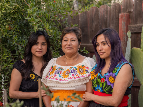 Two young Indigenous women holding the arms of an older Indigenous woman 