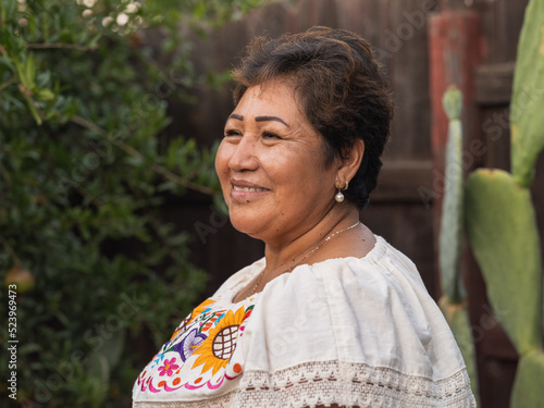 Horizontal image of an older Indigenous woman smiling in an outdoor setting 