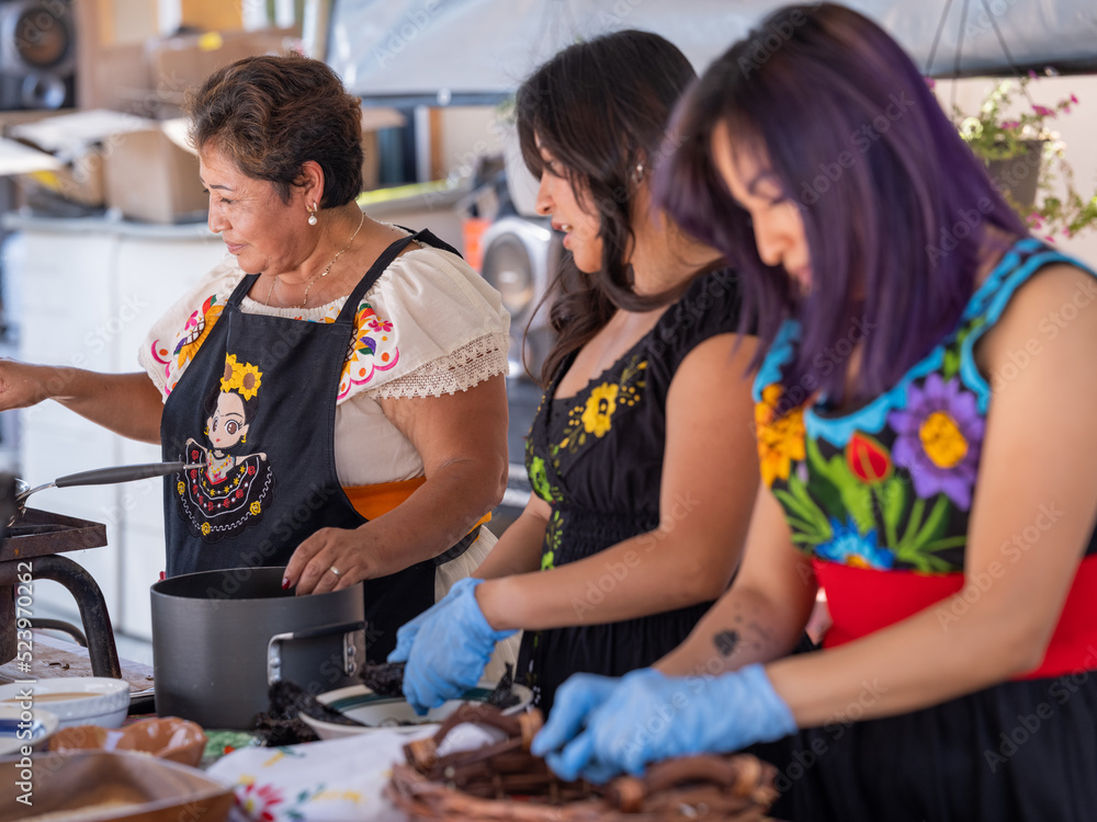 Horizontal image of an Indigenous family conversing while cooking