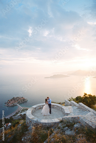 Obraz na płótnie Bride and groom kiss on the observation deck over the Sveti Stefan island