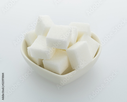 Sugar cubes in a heart shaped bowl on white background