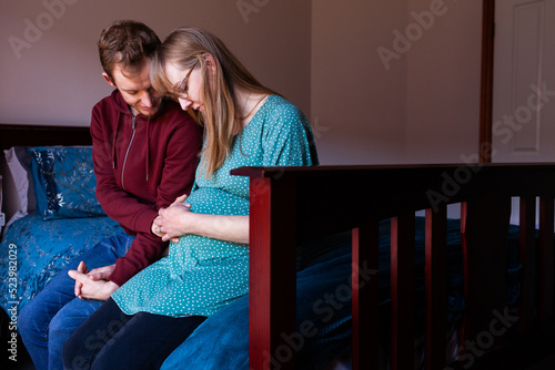 Young christian couple praying together in bedroom for unborn baby photo