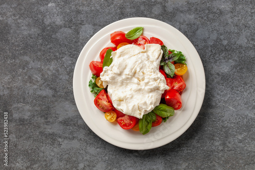 Italian salad cheese burrata or stracciatella with tomatoes on a plate. Top view