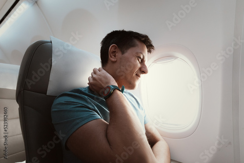 Quadro em tela A man suffers from severe neck pain during a long flight in an uncomfortable position on an airplane