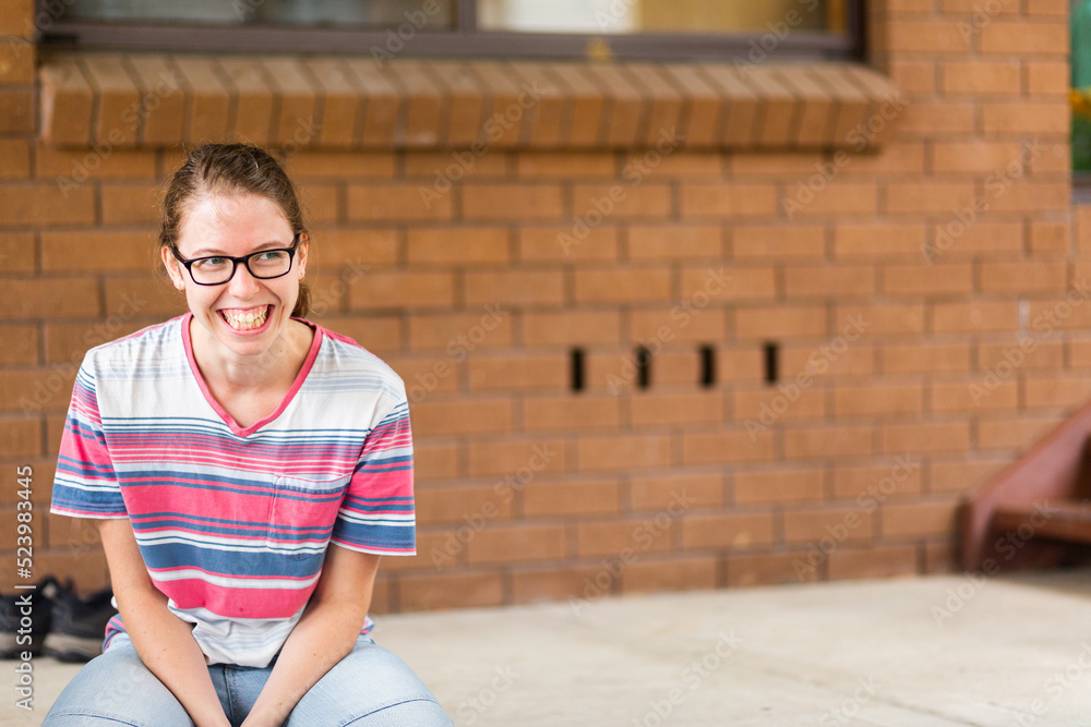 Teen girl laughing outside brick building with copy space Teen girl laughing outside brick building with copy space
