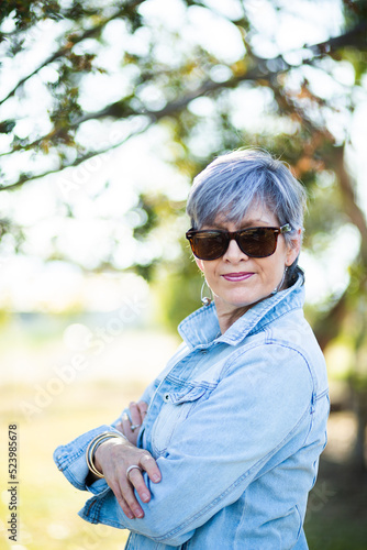 portrait of a senior woman in the garden wearing sunglasses photo