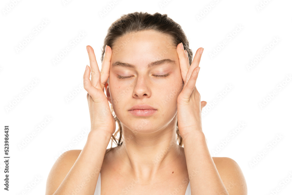 Young woman tightening her face skin with her palms on a white background. Young woman tightening her face skin with her palms on a white background.